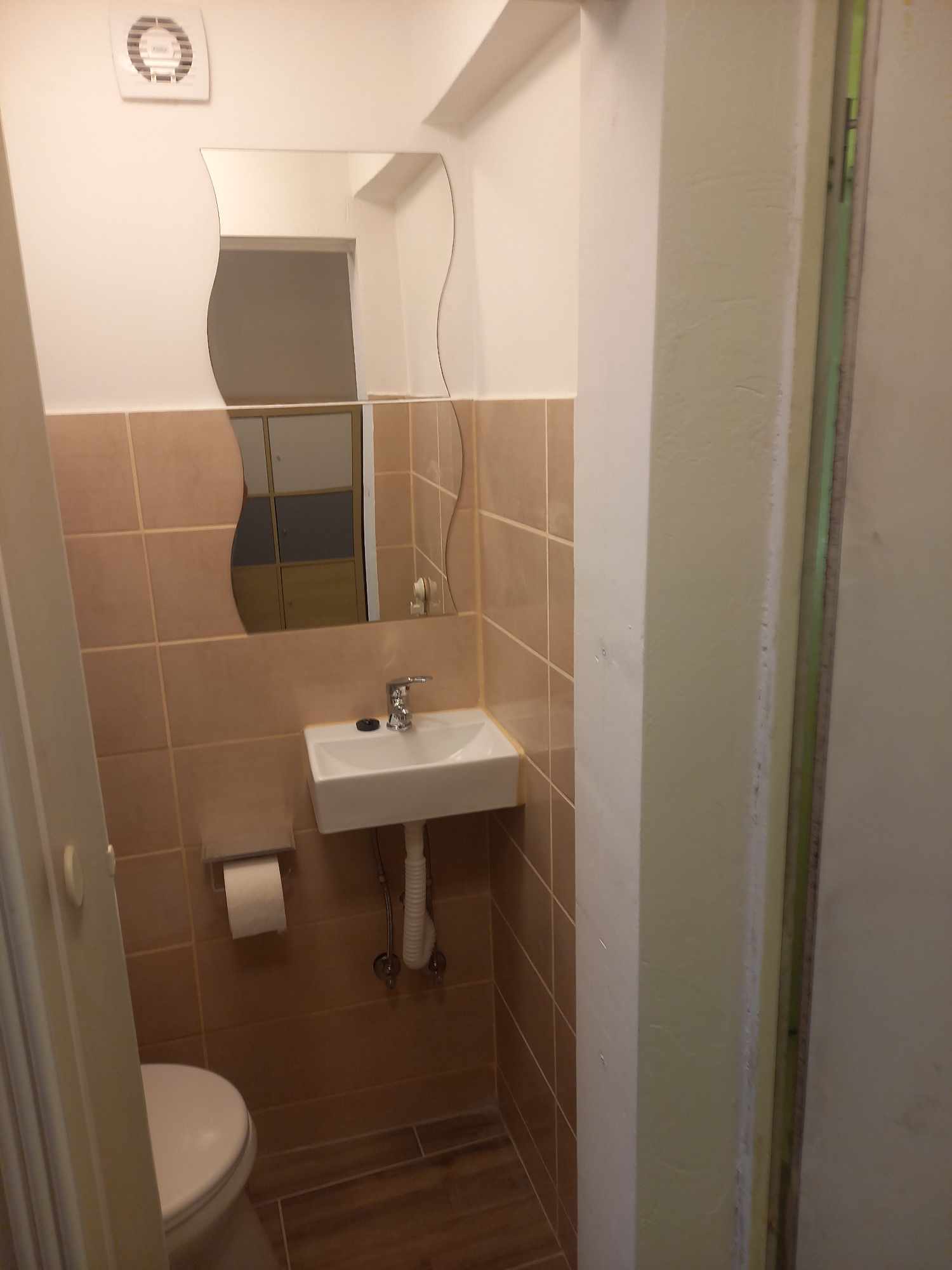 Felújított mini garzon kis WC helyisége kézmosóval és burkolattal