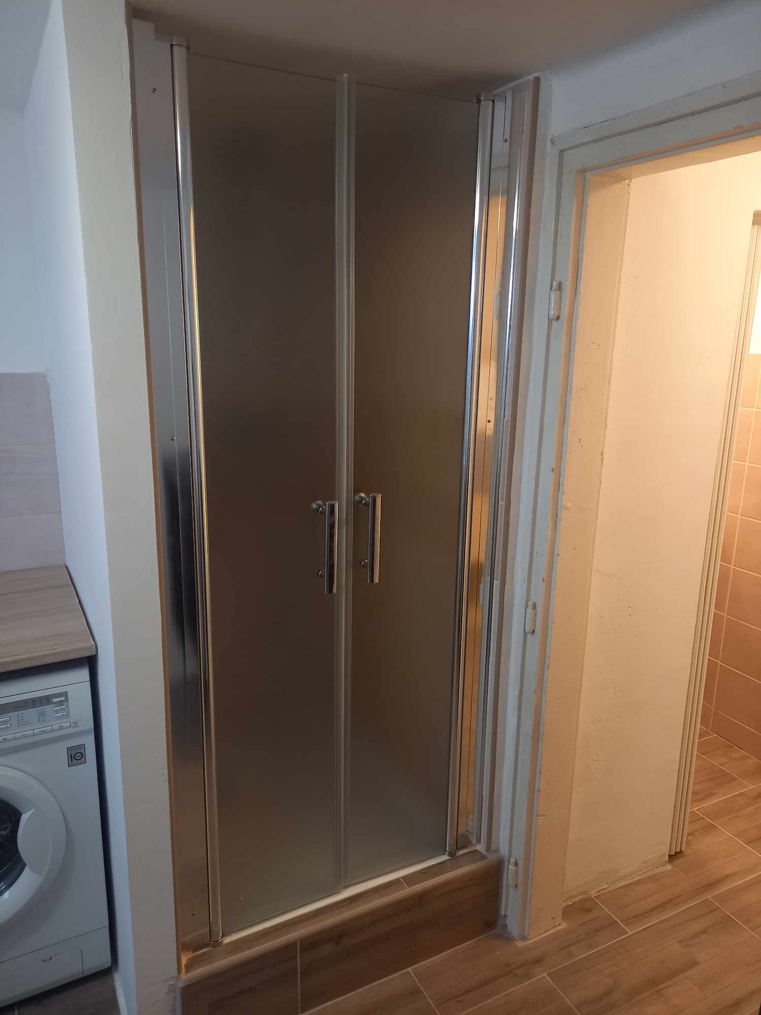 Mini garzonban kialakított zuhanyzó és mosógép melletti vizesblokk